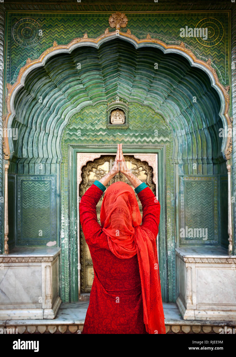 Indische Frau in Rot Schal mit Hände im Gebet Geste am grünen Tor im City Palace Jaipur, Rajasthan, Indien. Platz für Ihren Text, kann verwendet werden Stockfoto