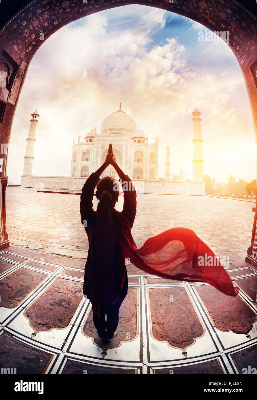 Frau Yoga tadasana tree Pose mit fliegenden roten Schal in Silhouette in der Nähe des Taj Mahal in Agra, Uttar Pradesh, Indien Stockfoto
