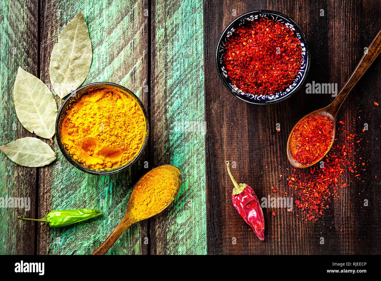 Chili, Paprika, Kurkuma und Lorbeerblätter auf Holz grün und braun Vorstand Hintergrund Stockfoto