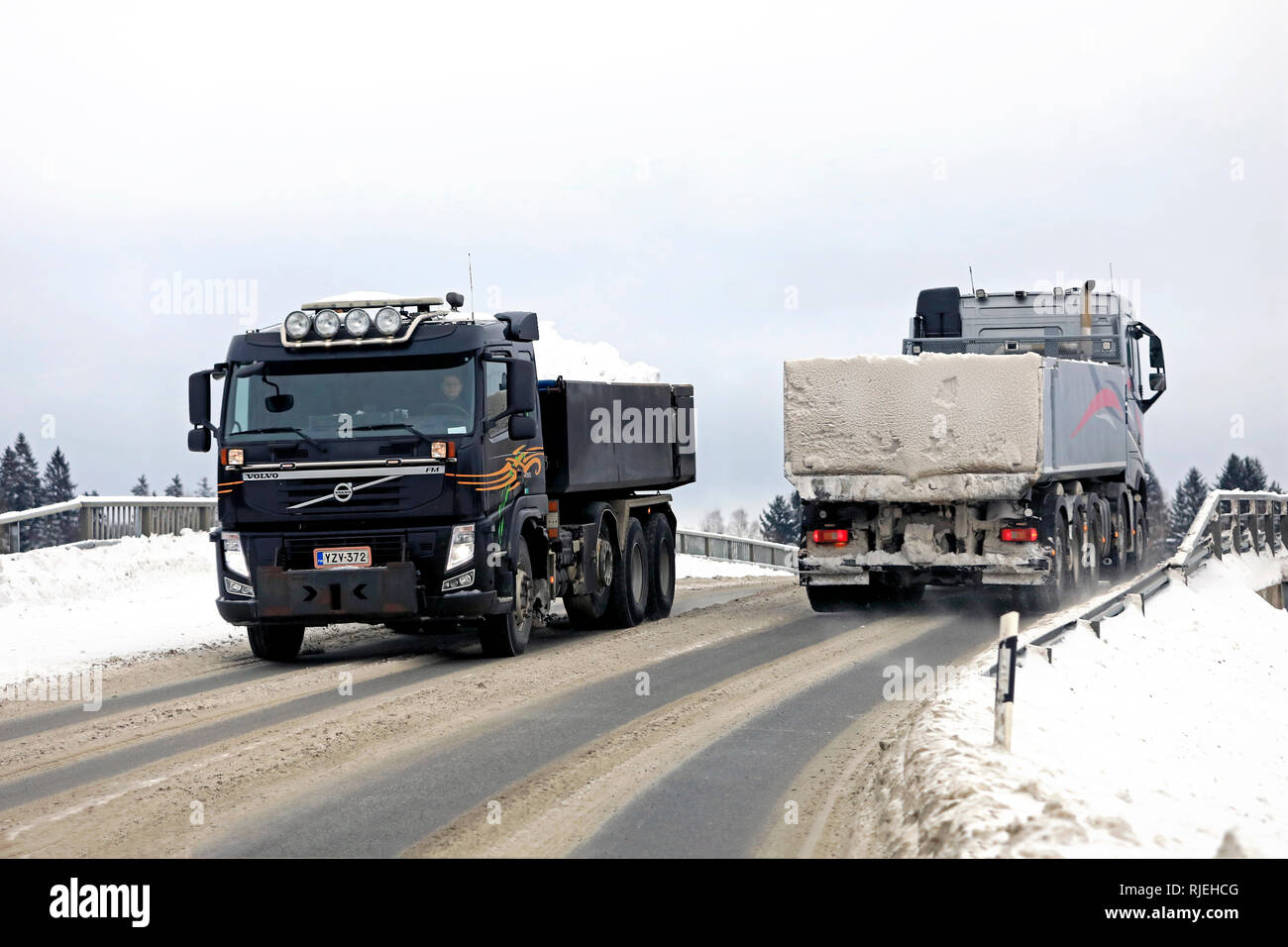 Salo, Finnland - Februar 2, 2019: Zwei Volvo Kipper auf einer Brücke bei Schnee haul Treffen weg von Stadt zu Stadt Schnee Dumping. Stockfoto