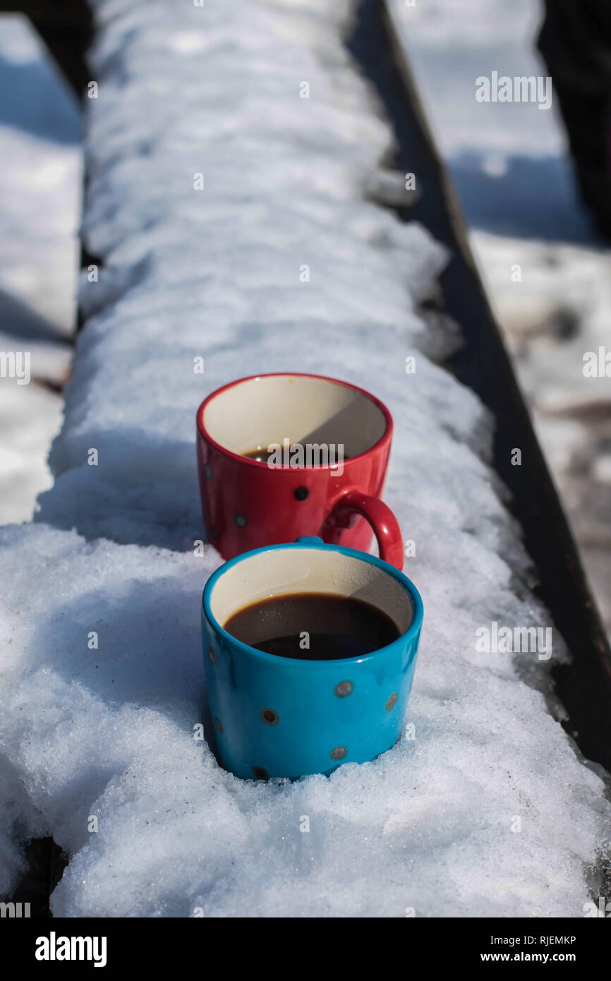 Zwei Tassen Kaffee und einem Donut auf der Bank mit Schnee bedeckt Stockfoto