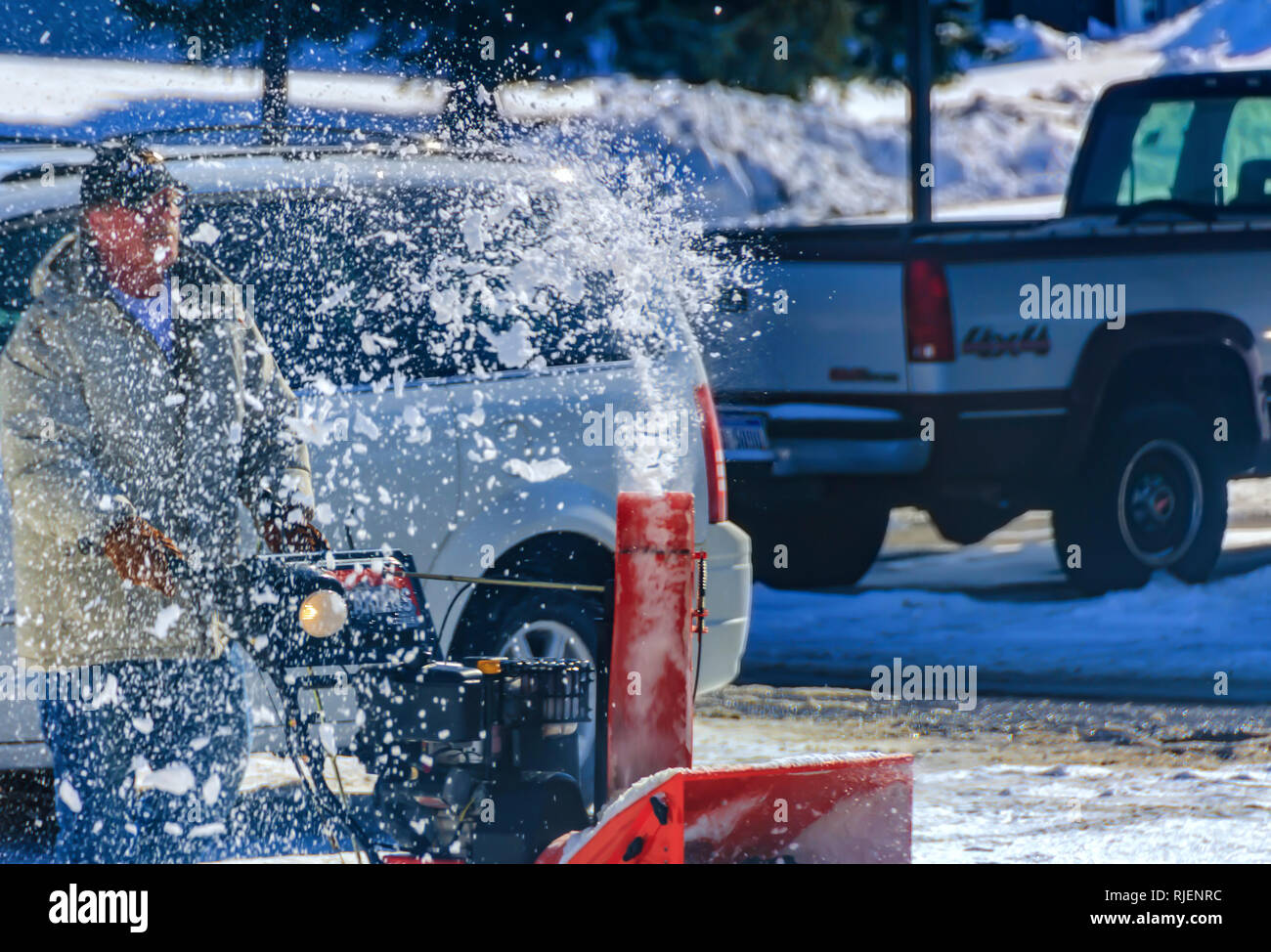 Brocken der Schneeschmelze sprudeln aus einer Schneefräse beim Schneeräumen nach einem Wintersturm in Michigan, USA. Bewegung eingefroren über schnelle Verschlusszeit. Stockfoto
