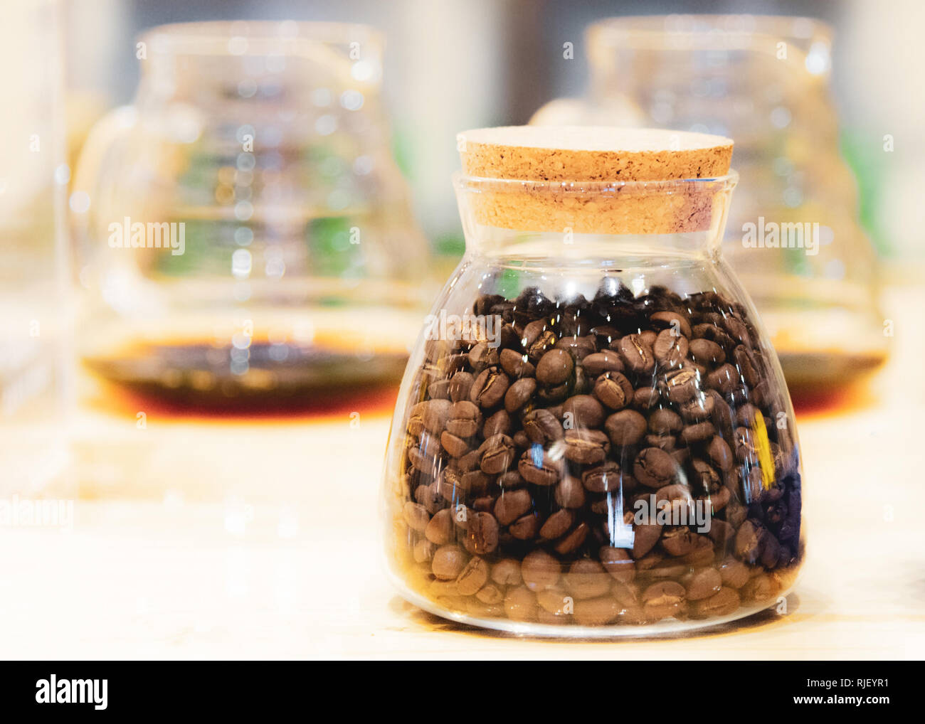 Kaffeebohnen in einem Glas Container auf hölzernen Tisch Stockfoto