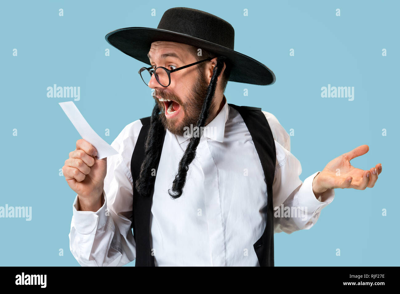 Portrait einer jungen orthodoxen Hasdim jüdischen Mann mit Wettschein im Studio. Das Holiday, Celebration, Judentum, Wette, Wetten. Stockfoto