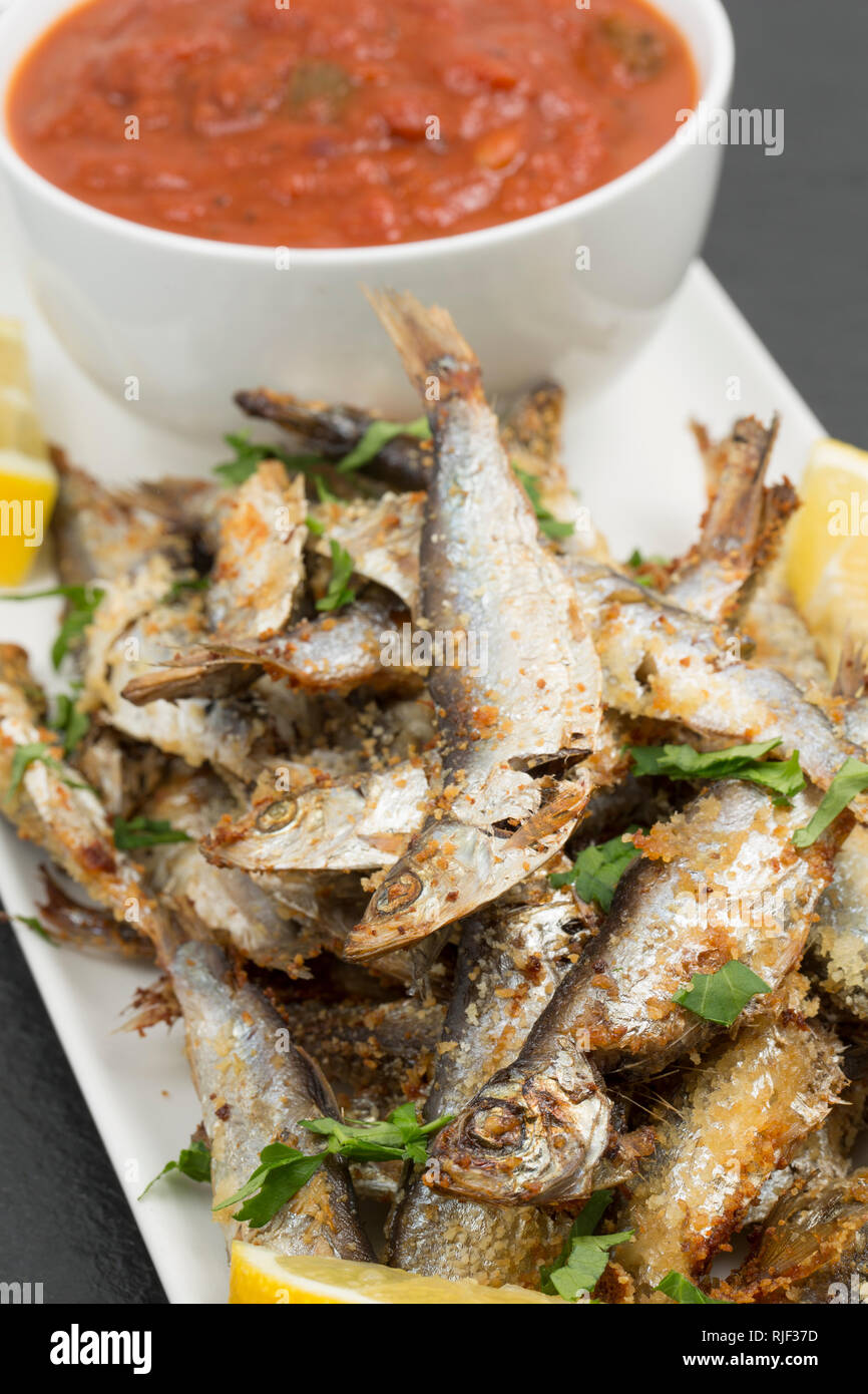 Hausgemachte Sprotten, Sprattus sprattus, aus einem Supermarkt, die mit oilve Öl- und Paniermehl, garniert mit Zitrone Keile und flache l gegrillt wurden. Stockfoto