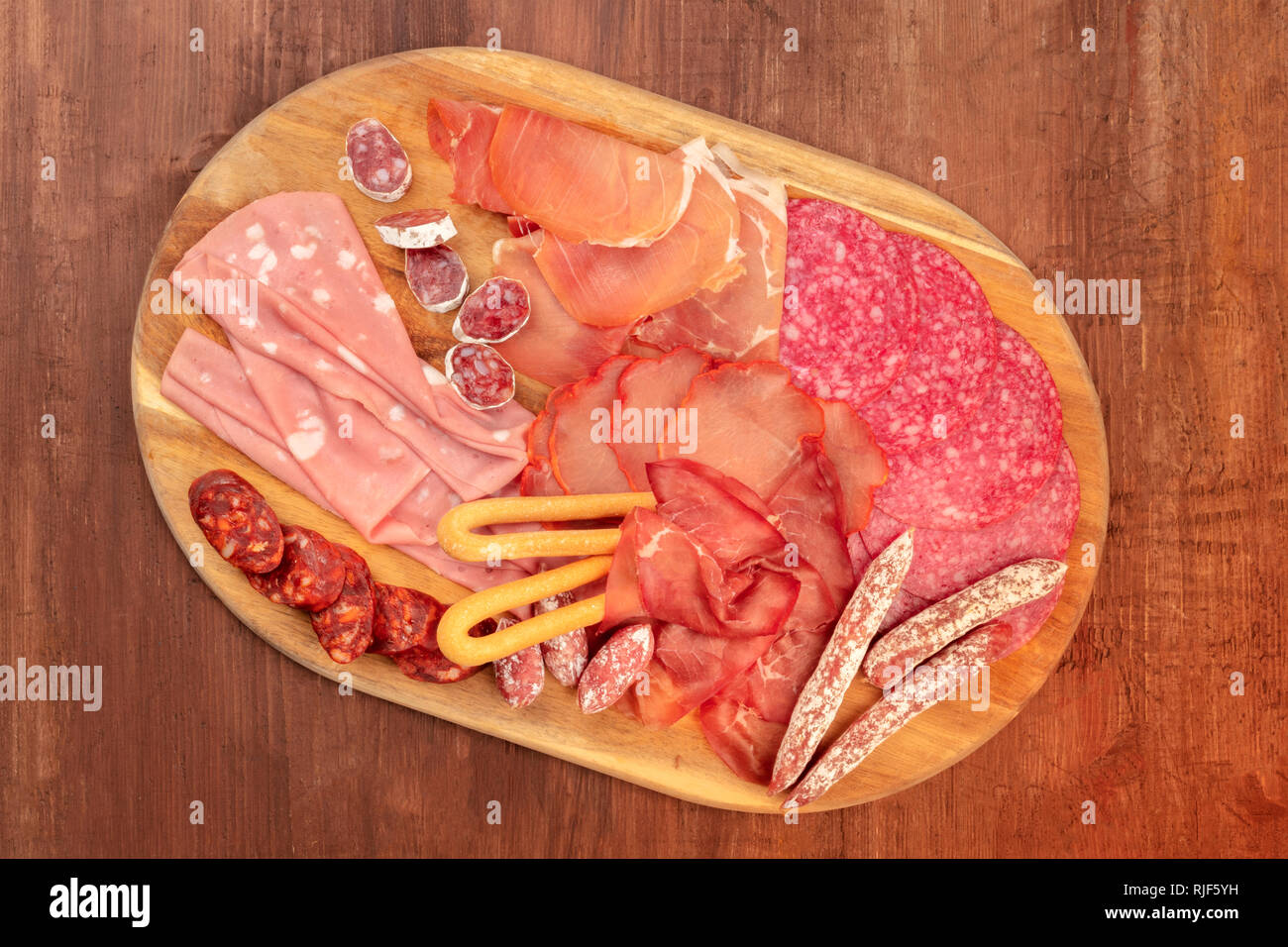 Charcuterie Verkostung. Ein Foto von einem Fach mit vielen verschiedenen Wurst und Schinken, Aufschnitt, geschossen von oben auf einen dunklen rustikalen Hintergrund Stockfoto