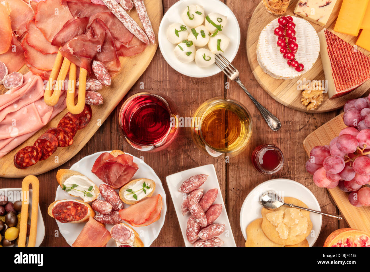 Charcuterie Verkostung. Viele verschiedene Wurst und Schinken, Aufschnitt, und einer Auswahl an Käse, geschossen von oben auf eine rustikale Hintergrund mit Brille Stockfoto