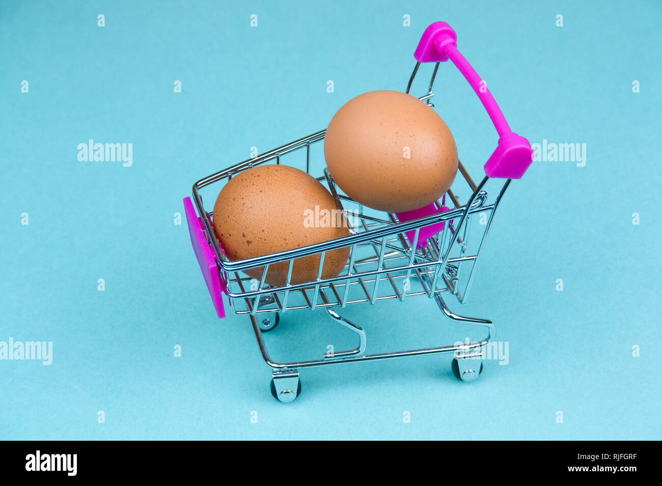 Braune Eier in Shopping Card auf einem blauen Hintergrund Stockfoto