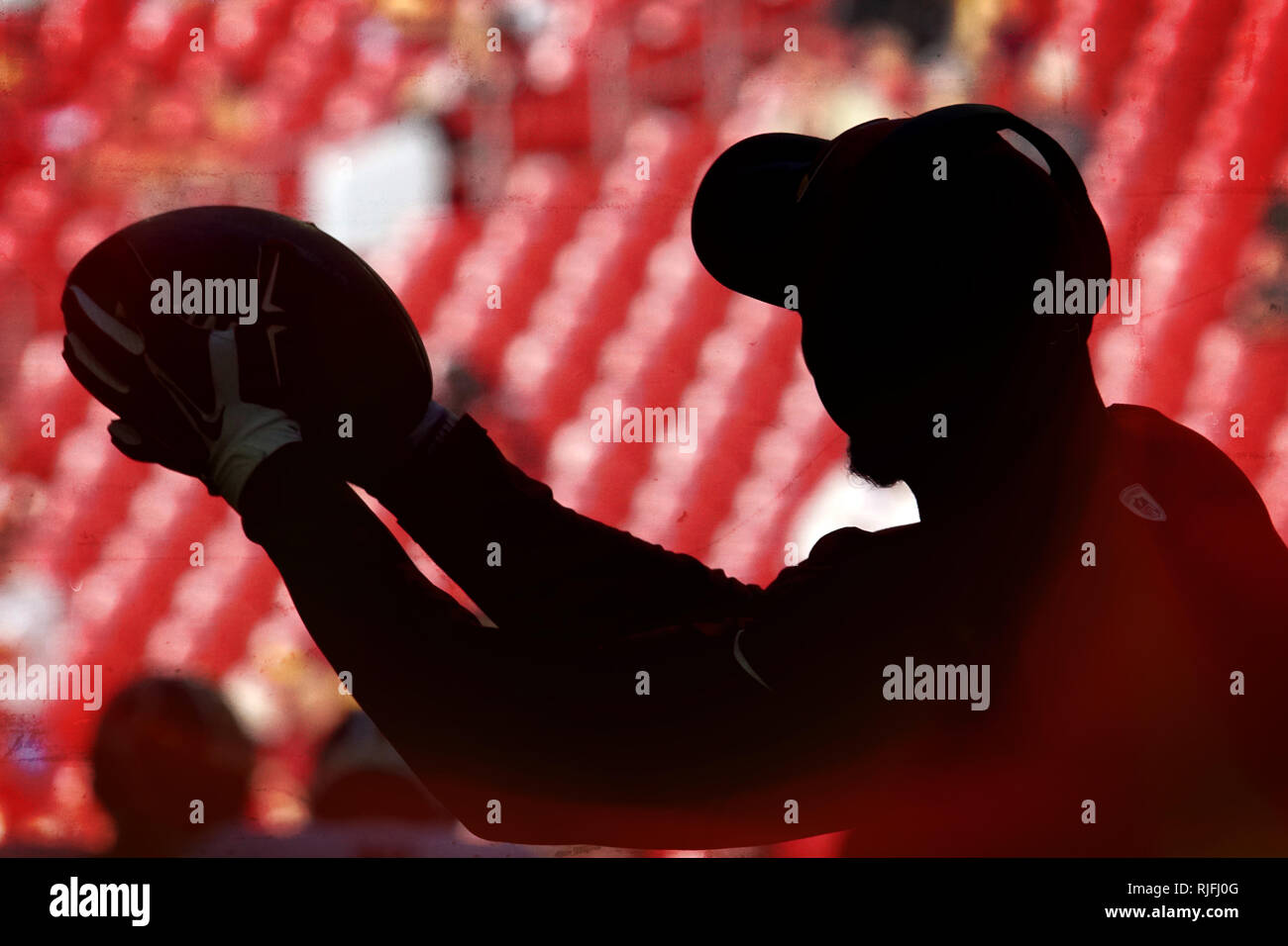 Während der pregame eines NFL Spiel die Silhouette eines Spieler der Fußball während des Warm ups Fänge. Stockfoto