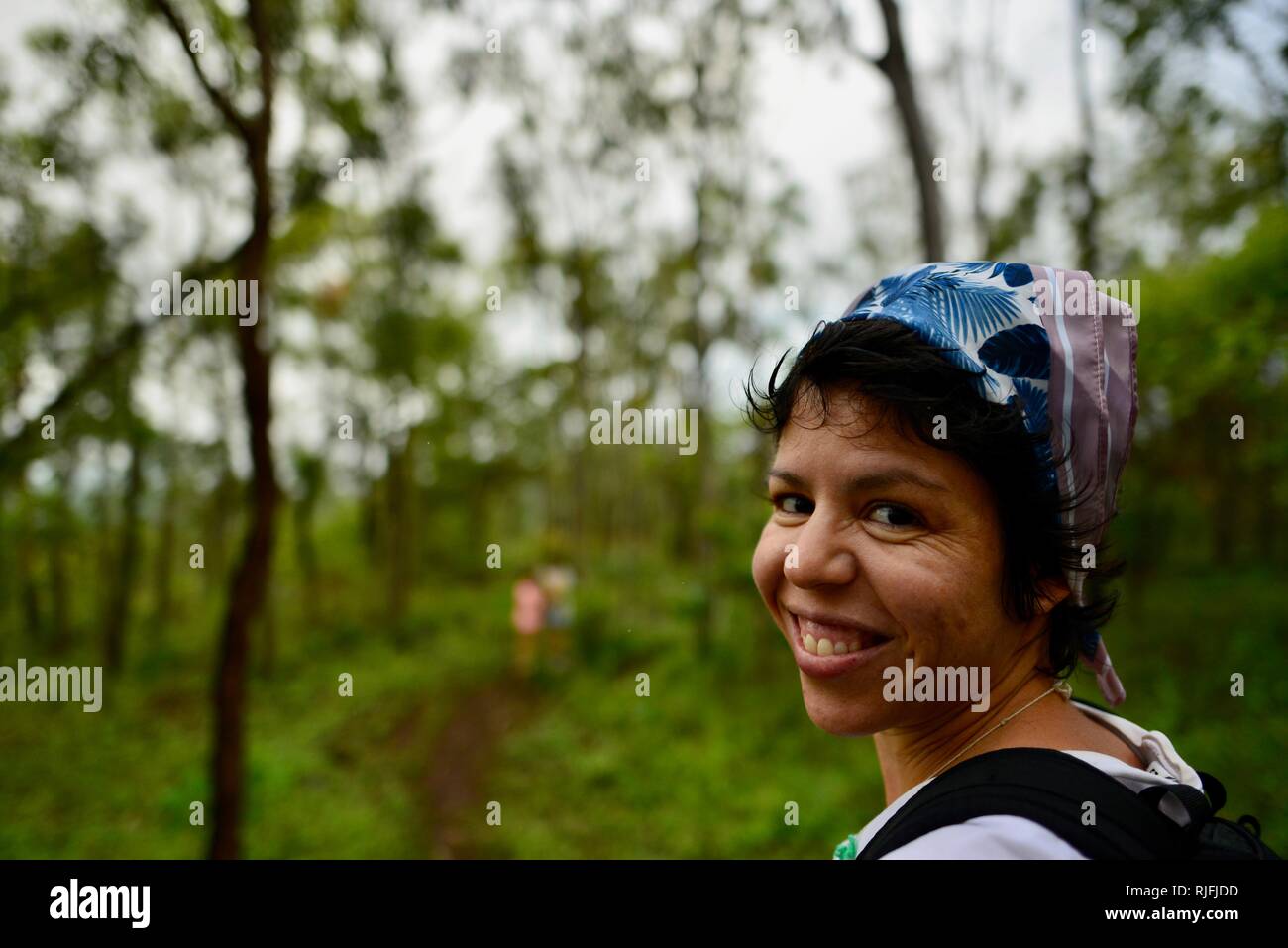 Frau lächelnd in die Kamera als junge Kinder im schulpflichtigen Alter an einem Feldweg in der Ferne, Townsville, Queensland, Australien Stockfoto