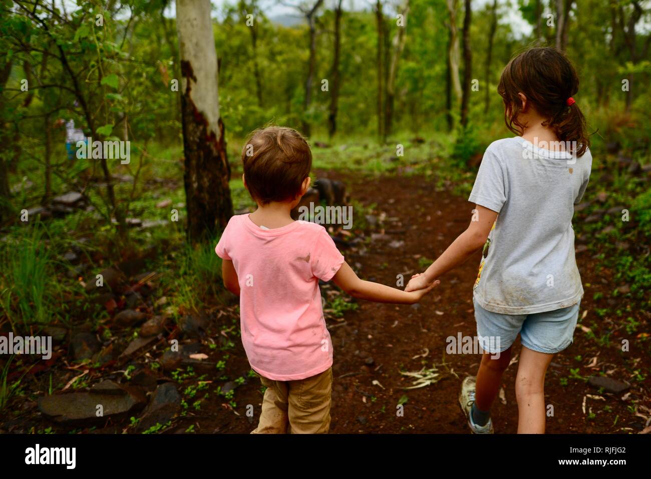 Junge Kinder im Schulalter entlang einem Feldweg, Hände halten, Moongun Wanderweg am Elliot Federn, Townsville, Queensland, Australien Stockfoto