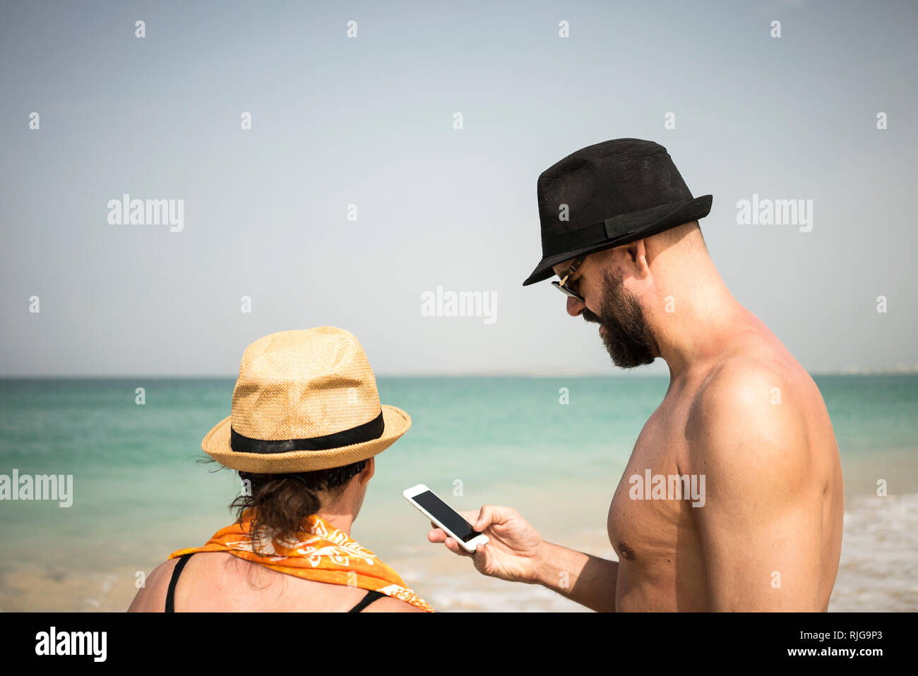 Paar am Strand mit Handy Stockfoto