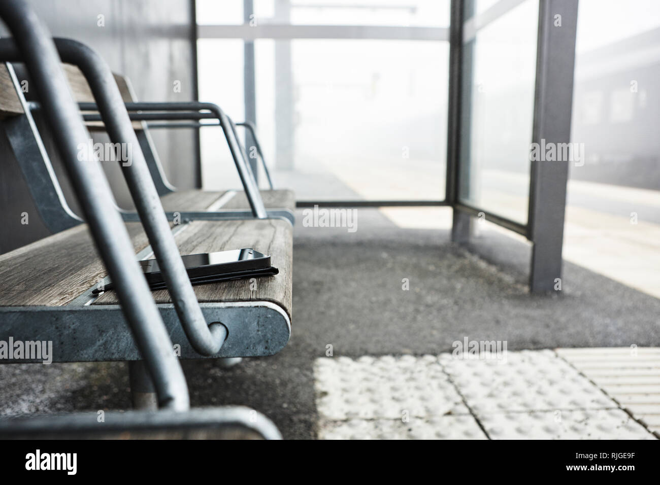 Handy auf Bahnsteig Sitz Stockfoto