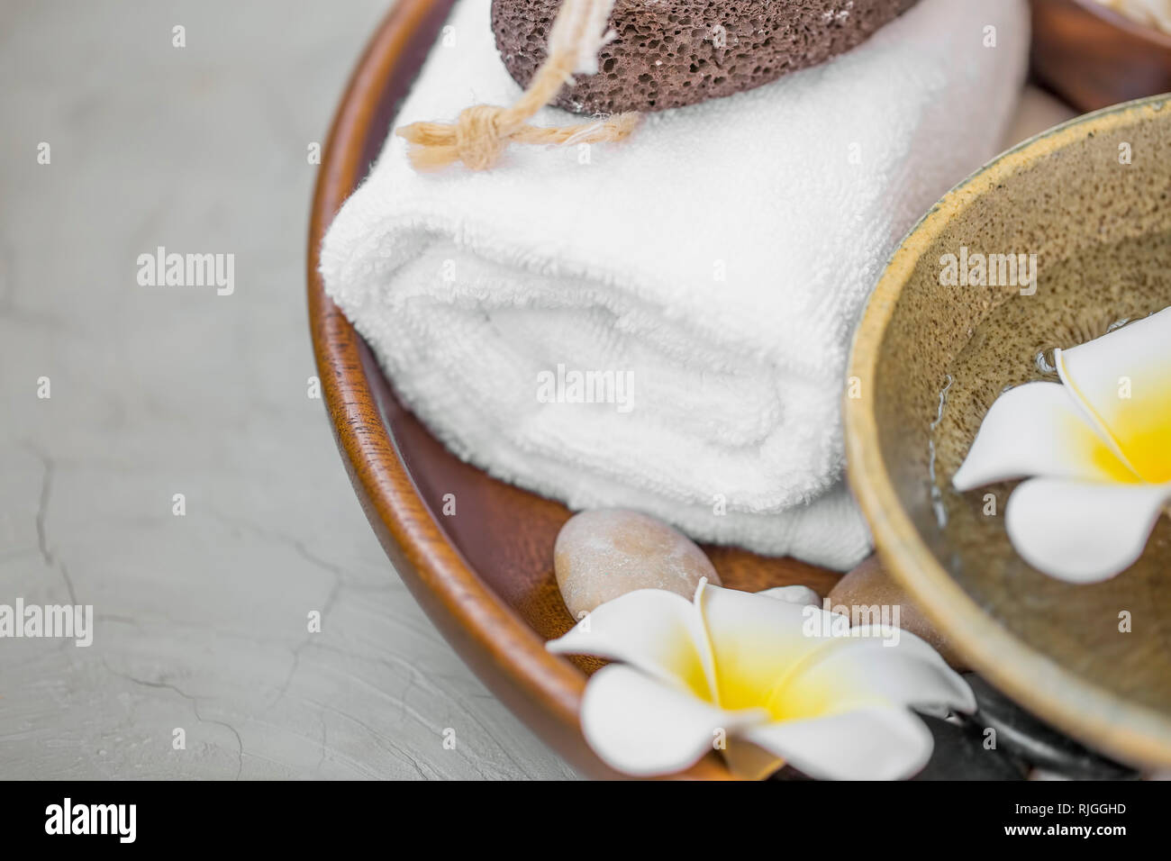 Spa noch Leben mit Baumwolle Handtuch, frangipani Blüten, Massage Steine in Holz- fach, selektiver Fokus, Wellness Produkte Details noch leben, Wellness backgr Stockfoto