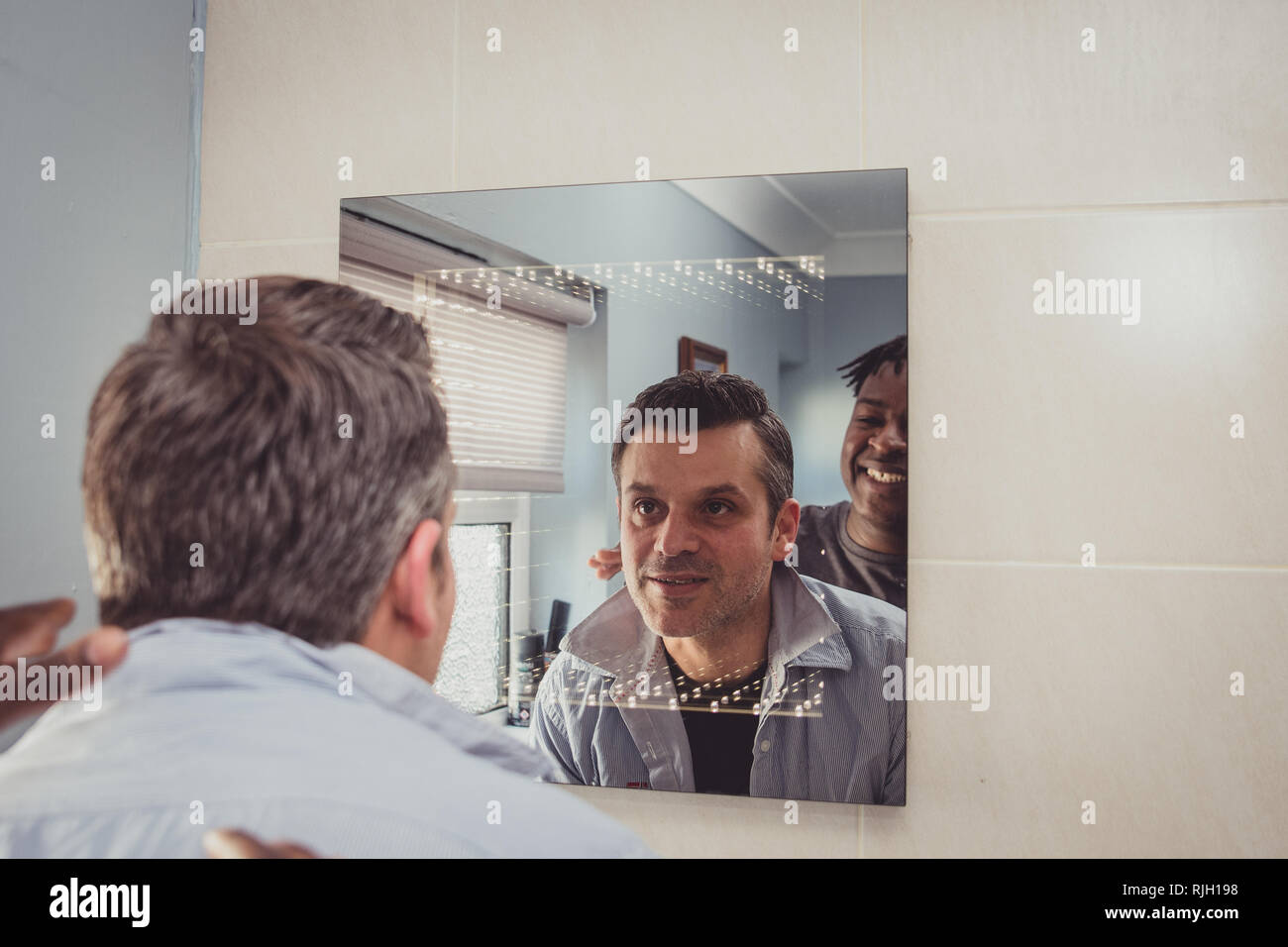 Ein homosexuelles Paar zusammen vor dem Badezimmerspiegel. Stockfoto