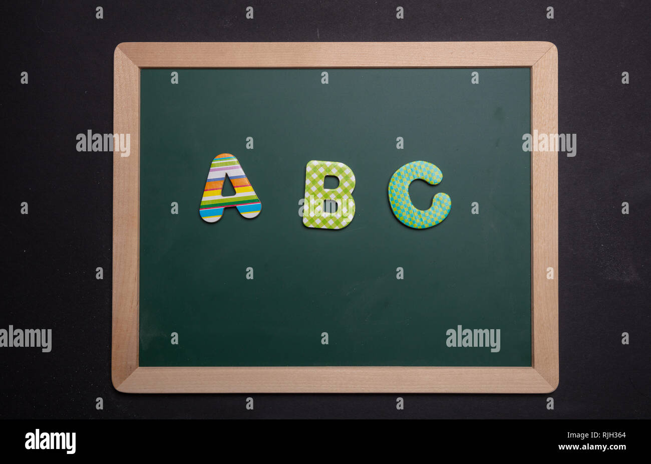 Abc, Alphabet, Schule Konzept. ABC Text mit bunten Buchstaben auf dem grünen Brett mit Holzrahmen, schwarz Farbe Hintergrund Stockfoto