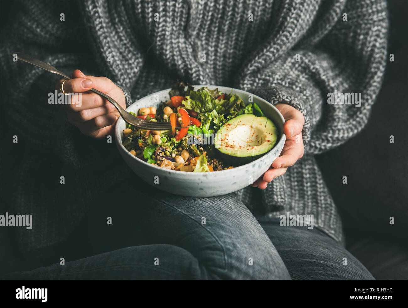 Frau in Pullover das Essen von frischem Salat, Avocado, Bohnen und Gemüse Stockfoto