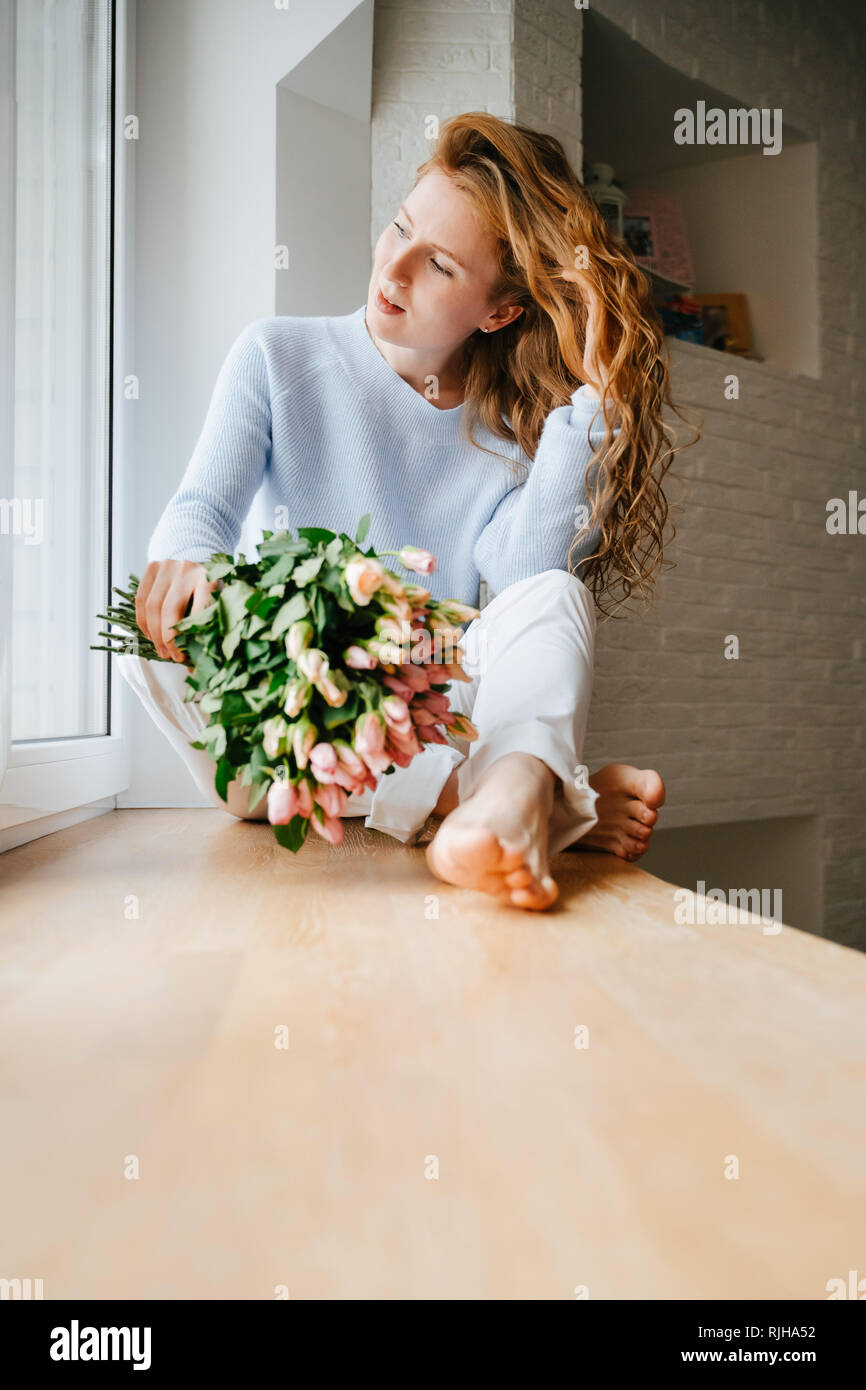 Portrait einer jungen schönen Mädchen mit einem Blumenstrauß aus Rosen in der Nähe der Fenster. Stockfoto
