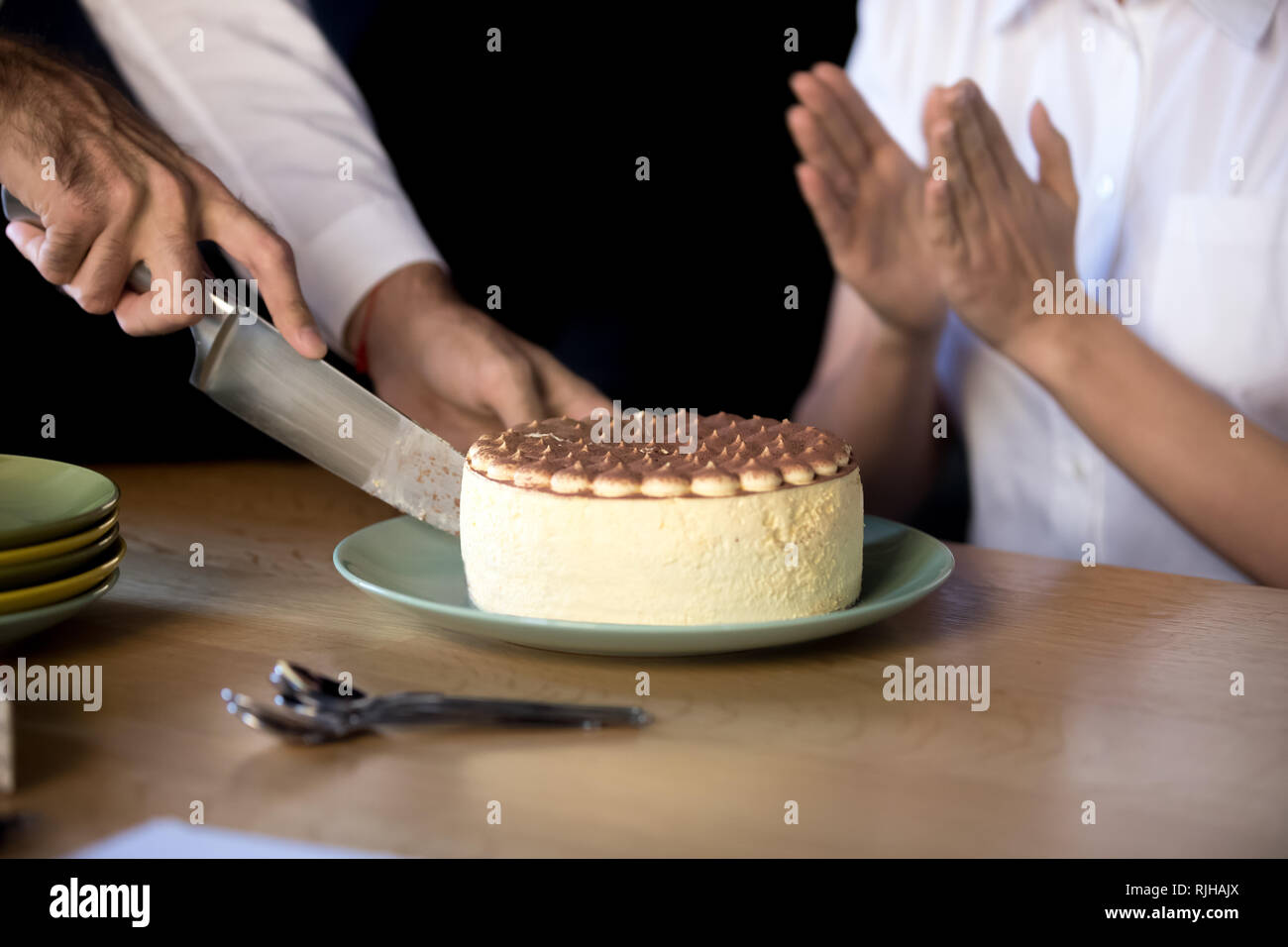 Nahaufnahme des Menschen schneiden Geburtstagstorte im Büro Stockfoto