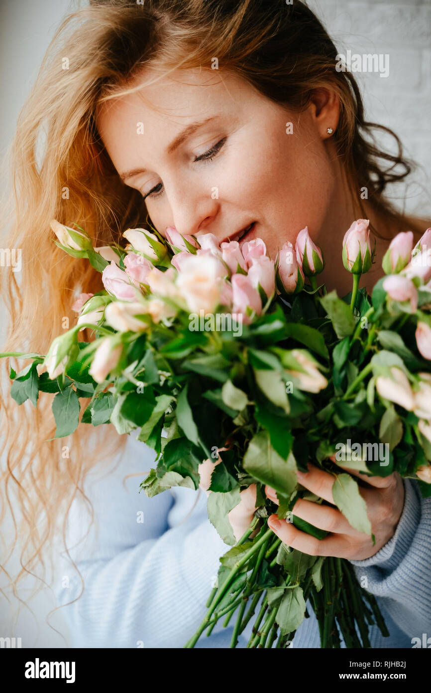 Portrait einer jungen schönen Mädchen mit einem Blumenstrauß aus Rosen in der Nähe der Fenster. Stockfoto