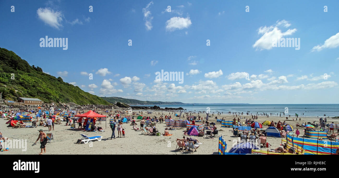 Besucher genießen die Sonne, Sand und Meer auf dem beliebten Strand von East Looe, Cornwall. Stockfoto