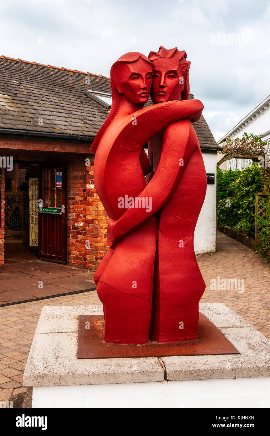Ein hohes rötlich-braune Skulptur (die Liebenden) ein Mann und eine Frau umarmen einander stehend von knapp über dem Knie auf einer niedrigen gepflasterte Sockel Stockfoto