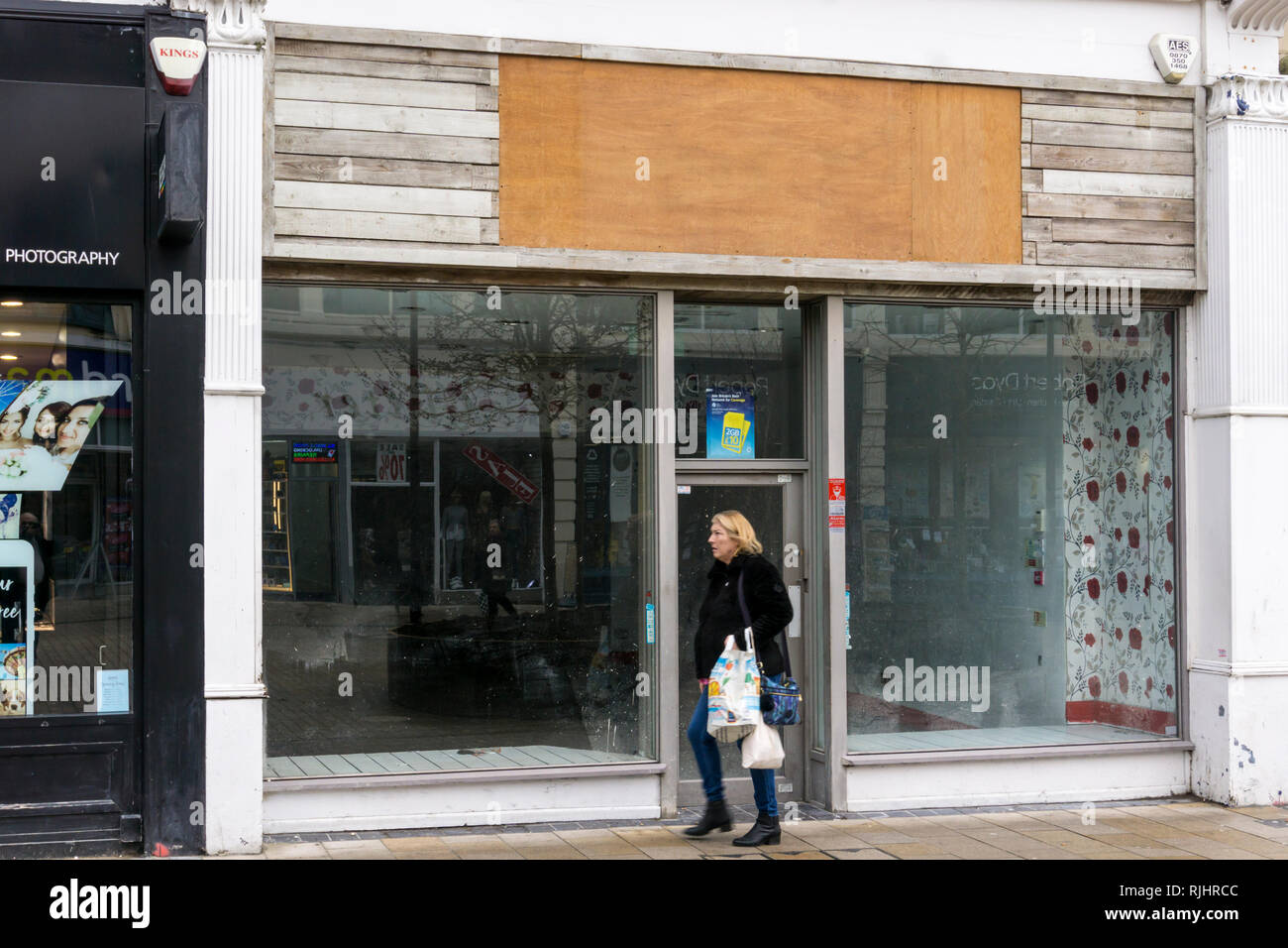 Frau hinter einem leeren Shop in Bromley High Street, London. Stockfoto