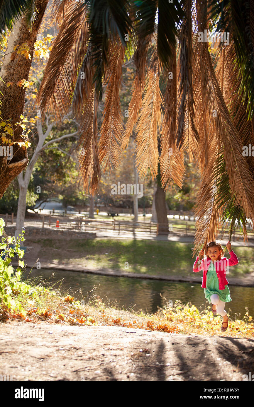 Junge Mädchen spielen mit einem Palm Tree Branch vor einem See. Stockfoto