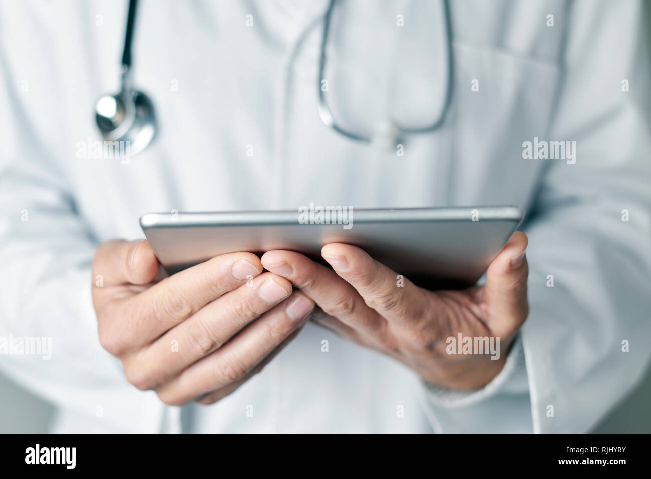 Closeup von einem kaukasischen jungen Arzt Mann trägt einen weißen Mantel mit einem Tabletcomputer Stockfoto