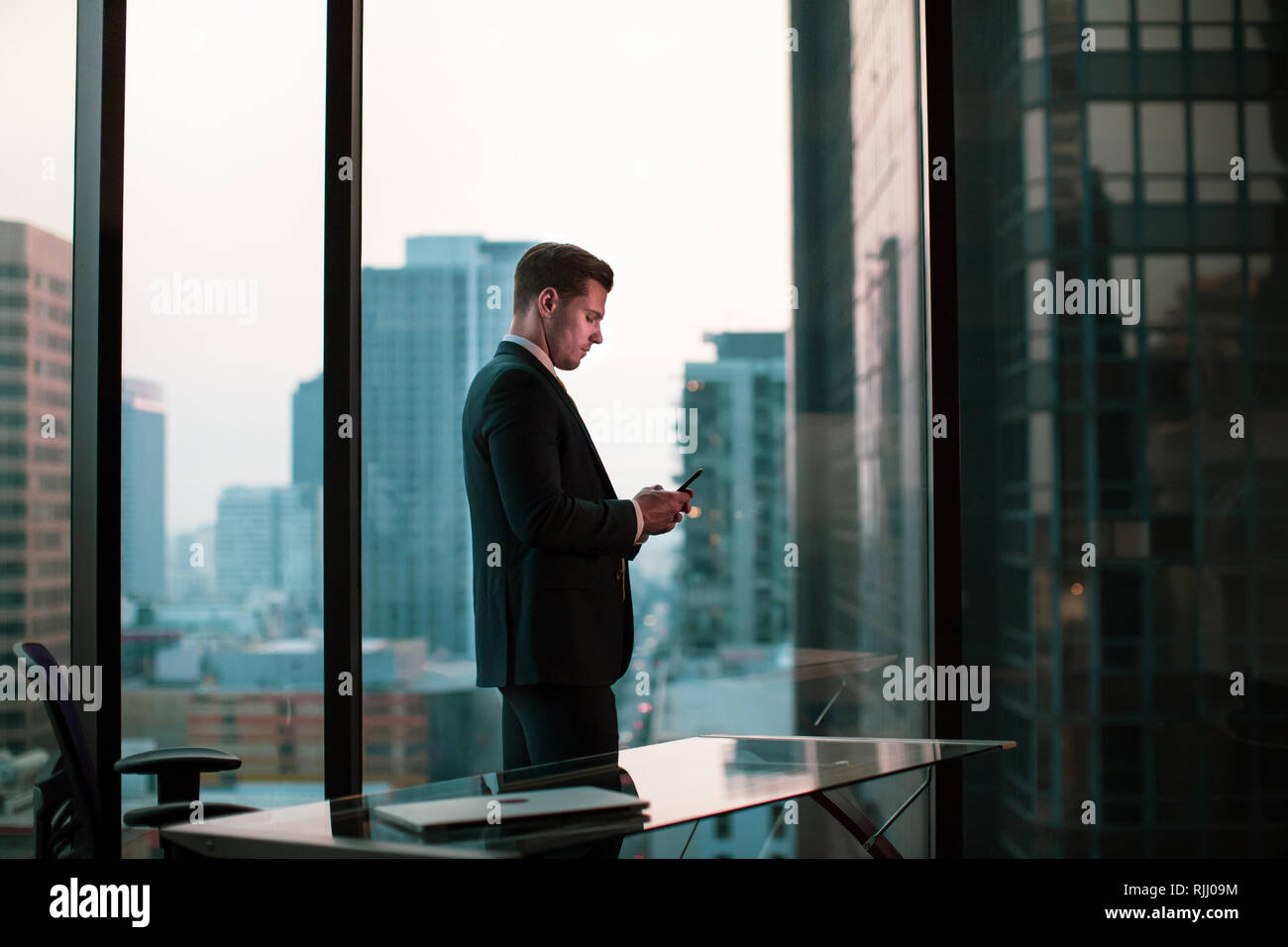 Geschäftsmann mit Smartphone in Wolkenkratzer Büro Stockfoto