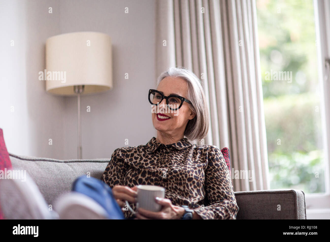 Reifen erwachsenen weiblichen zu Hause entspannen mit einem heißen Getränk Stockfoto