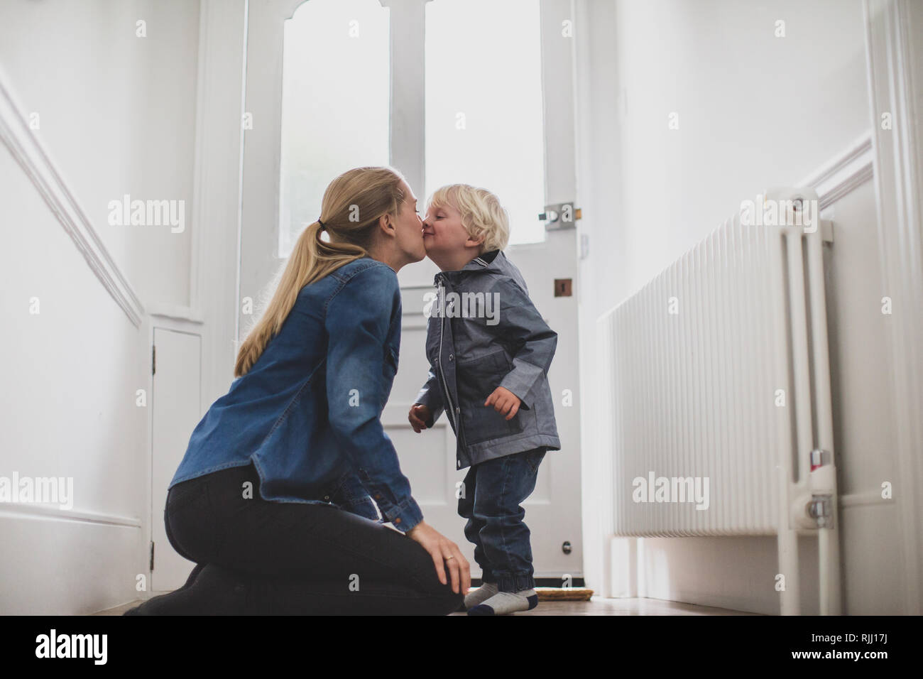 Mutter und Kind Abschied zu Hause küssen Stockfoto