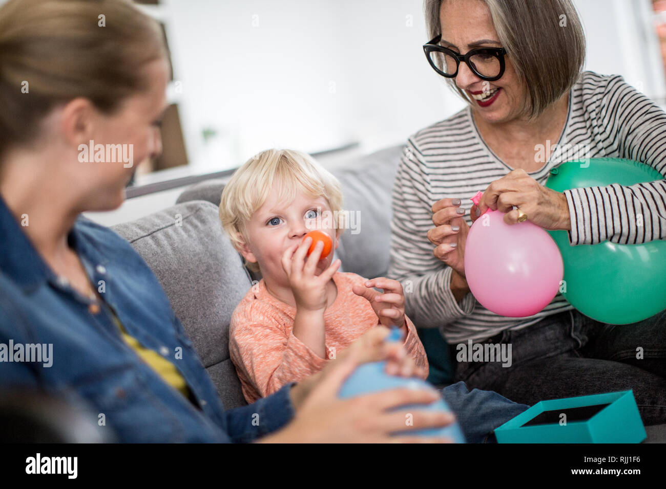 Junge sprengen Geburtstag Luftballons mit Familie Stockfoto