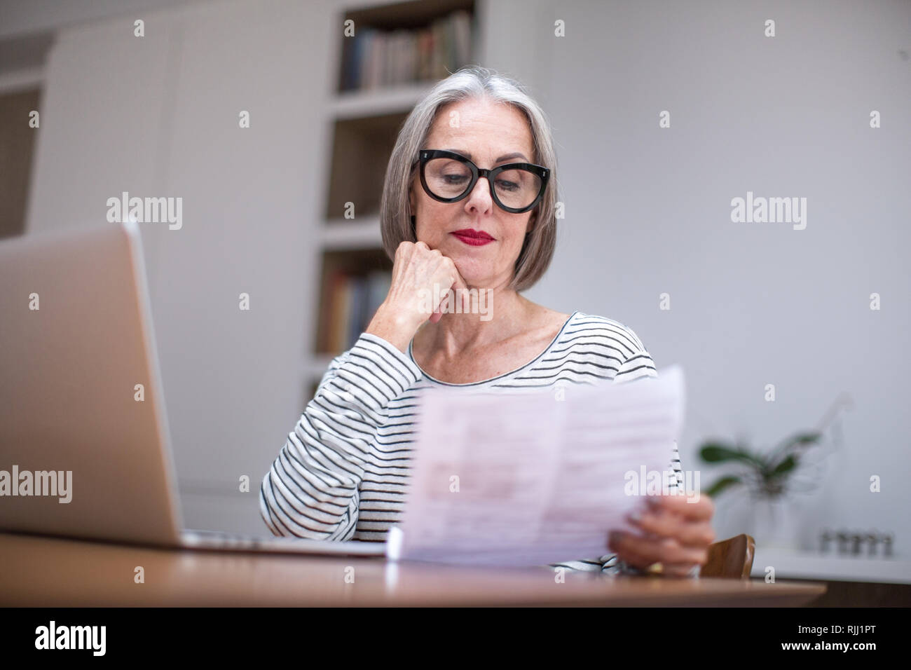 Reifen erwachsenen weiblichen bezahlen Rechnung online mit einem Laptop Stockfoto