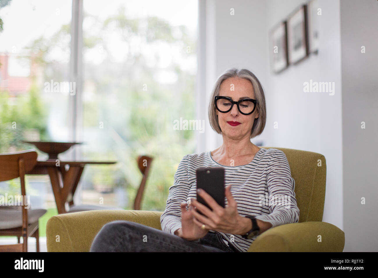 Reifen erwachsenen Weibchen mit einem Smartphone zu Hause Stockfoto