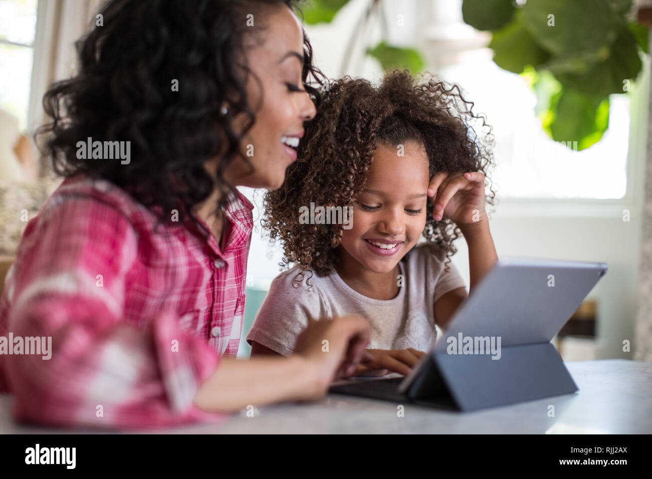 Afrikanische amerikanische Mutter, Tochter mit den Hausaufgaben mit digitalen Tablet Stockfoto