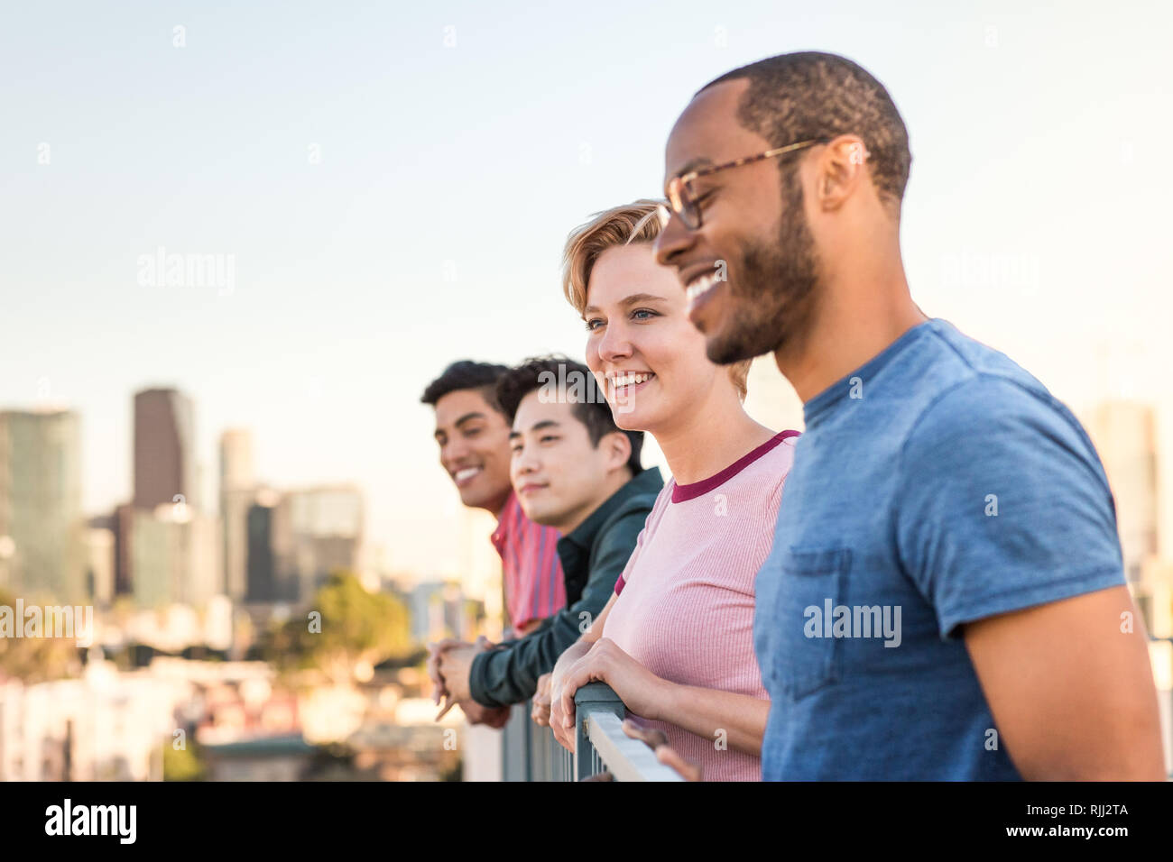 Eine Gruppe von Freunden mit Blick auf die Skyline der Stadt, die auf einem Dach Stockfoto