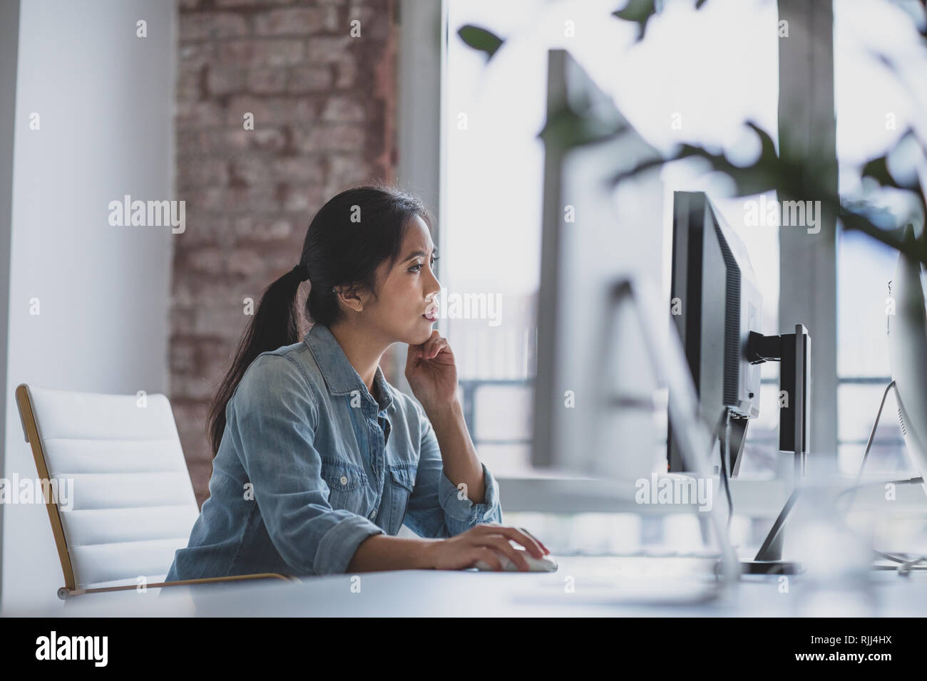 Junge erwachsene Frau die Arbeit in einem Büro auf einem Desktop-Computer Stockfoto