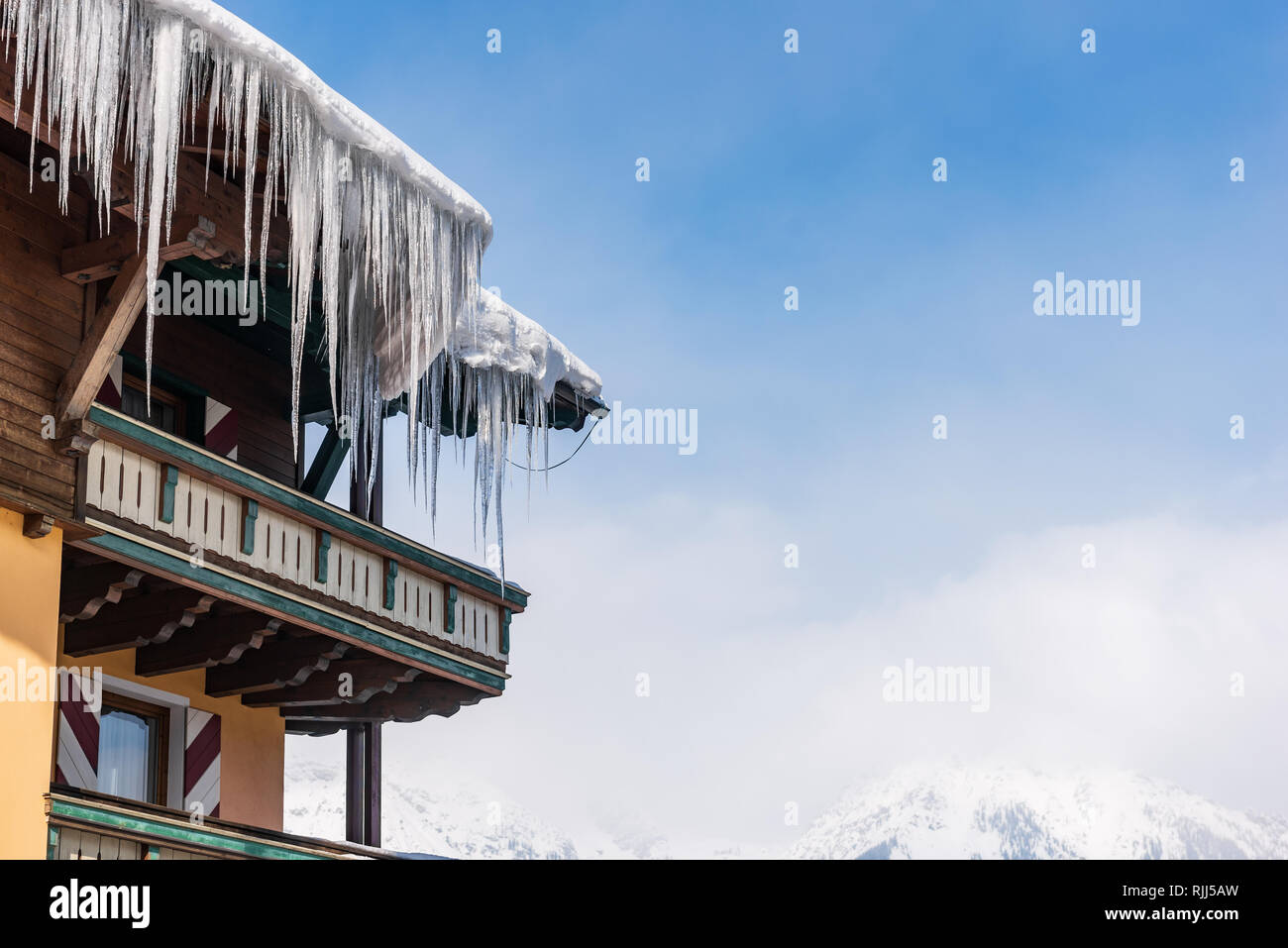 Großen Eiszapfen über die Regenrinne auf einem Dach eines traditionellen Holz- Haus in den Bergen hängen im Winter gefährlich sein könnte. Stockfoto