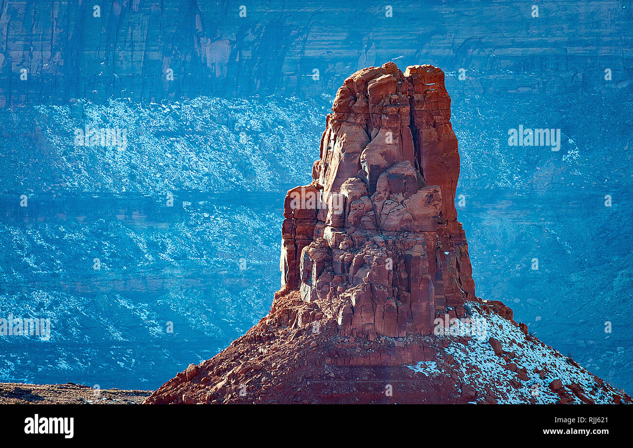 Januar 2019: Ein hoch aufragenden Turm über dem Schnee bedeckten Wänden aus rotem Sandstein und weißem Rim Trail, Dead Horse Point State Park, Moab, Utah. Stockfoto