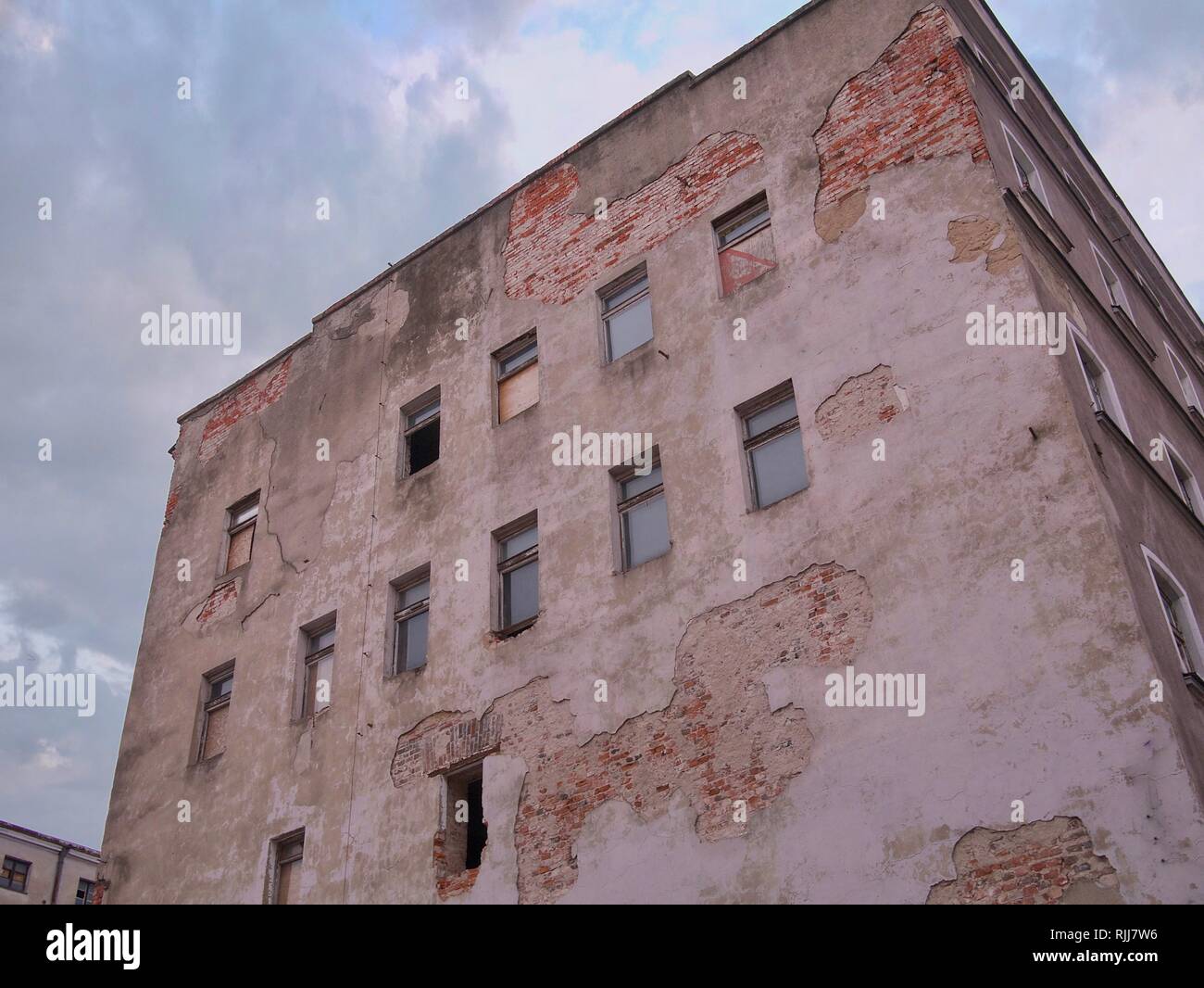 Alte und verwitterte Aufgegeben unbewohnten Brick Wohngebäude mit Fassade fallen aus und zerbrochene Fenster Stockfoto