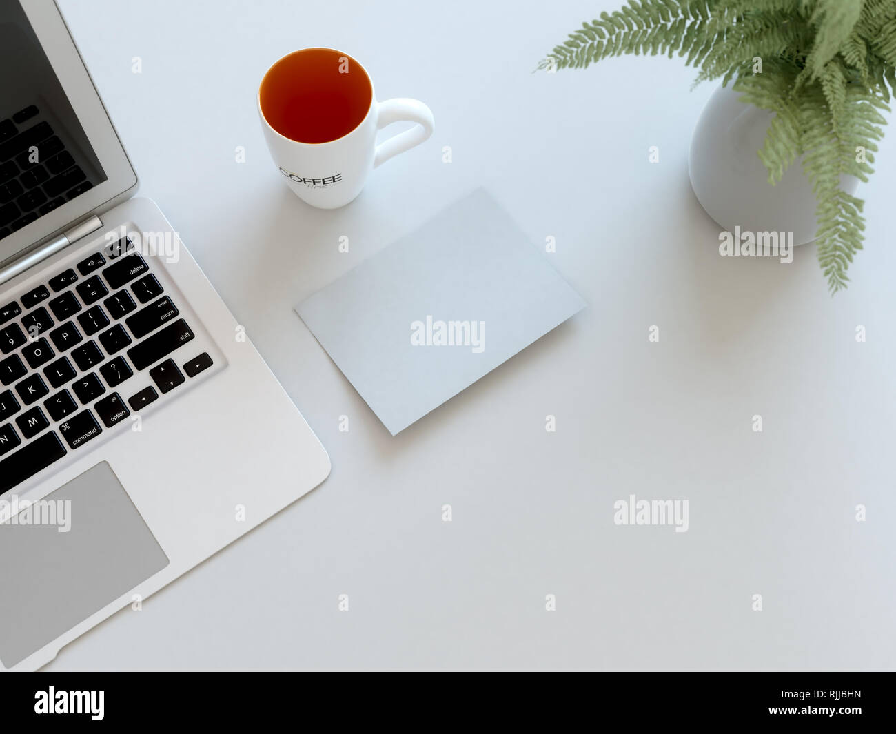 Ansicht von oben in einem Home Office Schreibtisch, mit einem Laptop, Kaffeetasse, eine Pflanze und ein Foto. Stockfoto