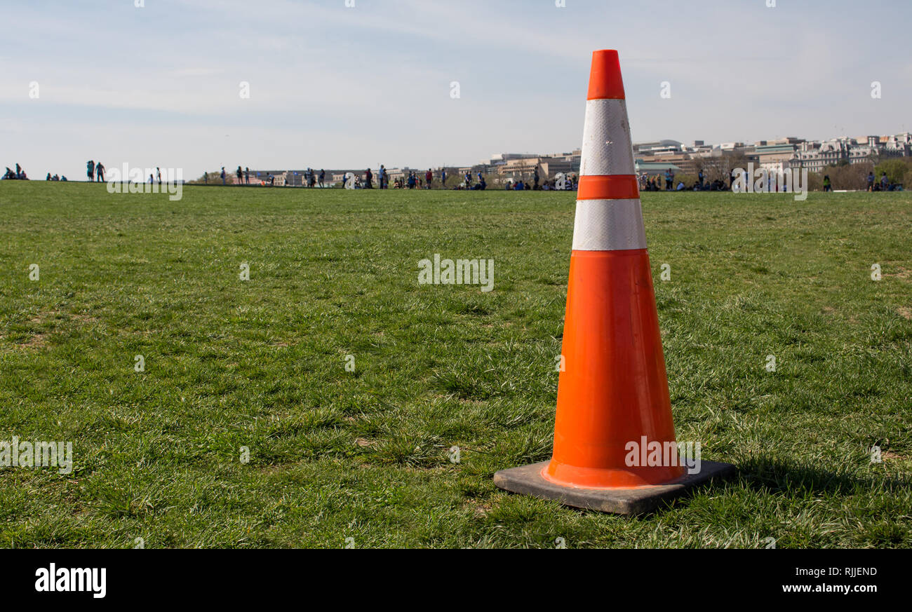 Nahaufnahme Foto einer orange Pylon in einem Park mit Menschen in der Ferne. Stockfoto