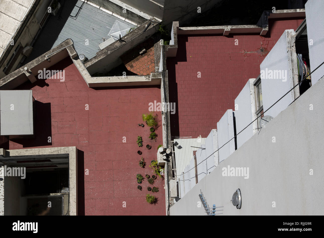 Blick von oben der Wohnung Gebäude mit kleinen Pflanzen, Tisch und Stühlen auf einer roten terracotta Hintergrund in Buenos Aires, Argentinien, Südamerika Stockfoto