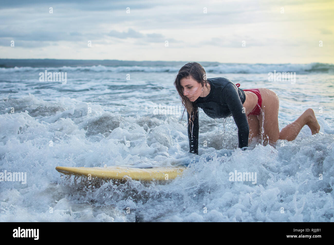 Aktion der jungen Frau versuchen Sie Schritt auf dem Surfbrett in die Med der Ozean, Reiten auf der Welle attemption Skill Training an Einsteiger auf Stockfoto