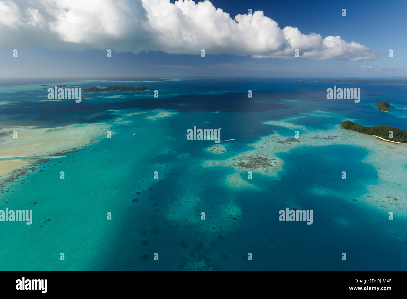 Antenne Landschaft der tropischen Inseln, flachen Korallenriffen und Boote unter geschwollene weiße Wolken Stockfoto