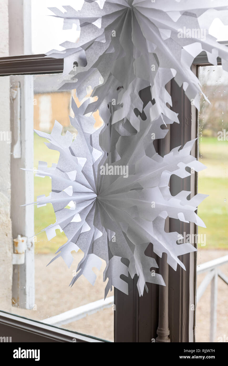 Traditionelle Papier Schneeflocke Dekorationen hängen im Fenster Stockfoto