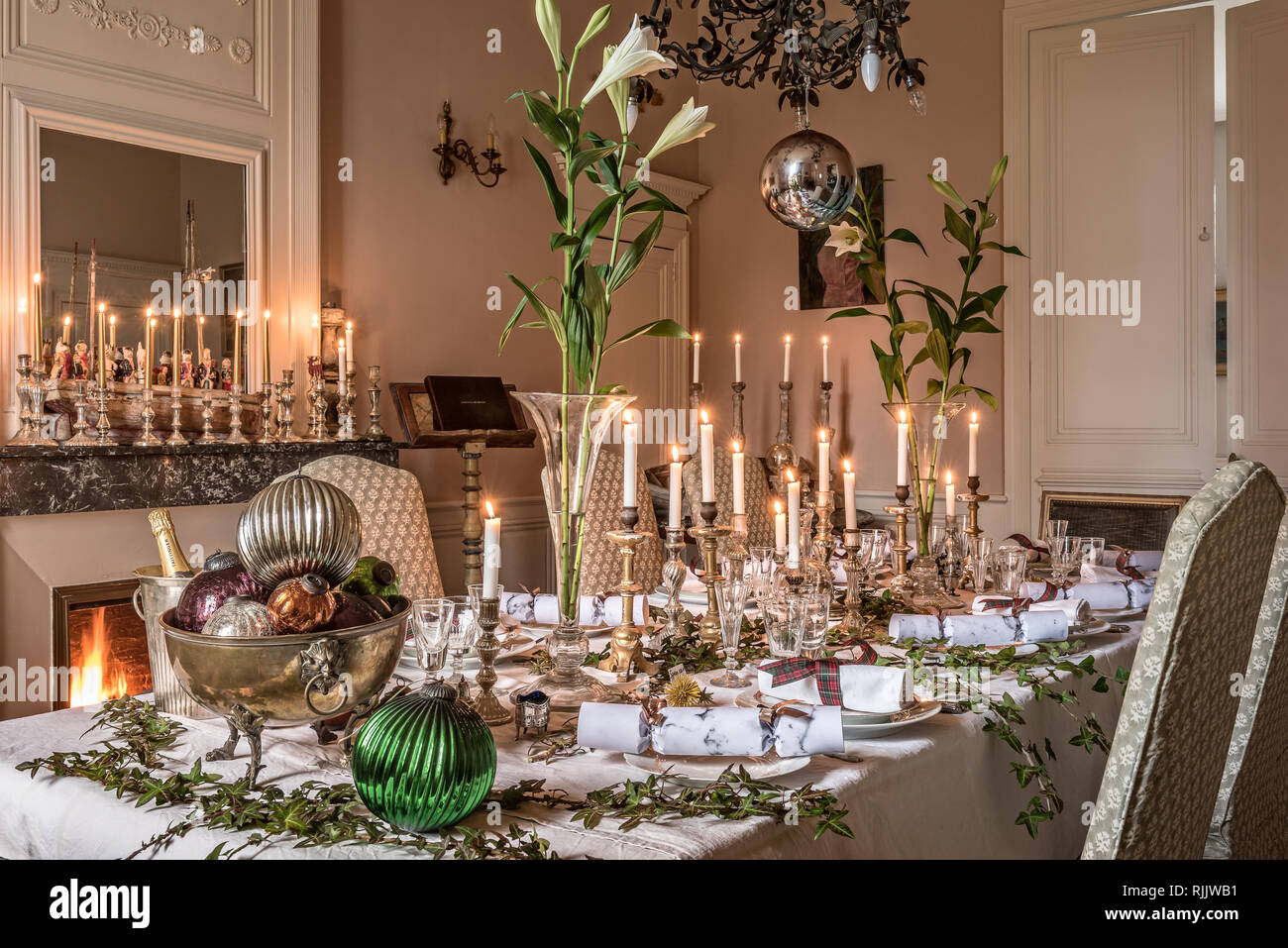 . Quecksilber Kerzenständer entlang der kamineinfassung mit mehr auf der Tabelle hinzufügen, um die festliche Gefühl des Besonderen mit Lilien gesäumt. Dekorative la Stockfoto