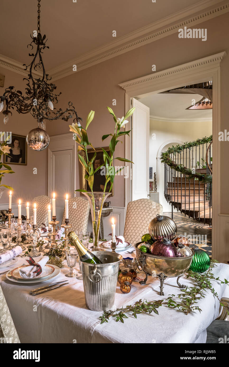 Quecksilber Kerzenständer auf dem Tisch mit Lilien unter dekorative Kronleuchter aus Kupfer aus dem späten 19. Jahrhundert. Stockfoto