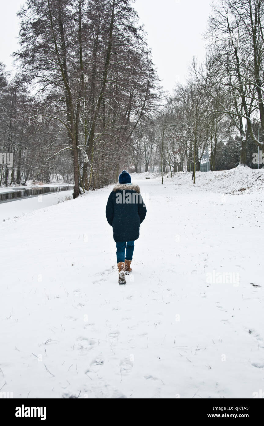 Frau alleine im Wald unter Schnee Stockfoto